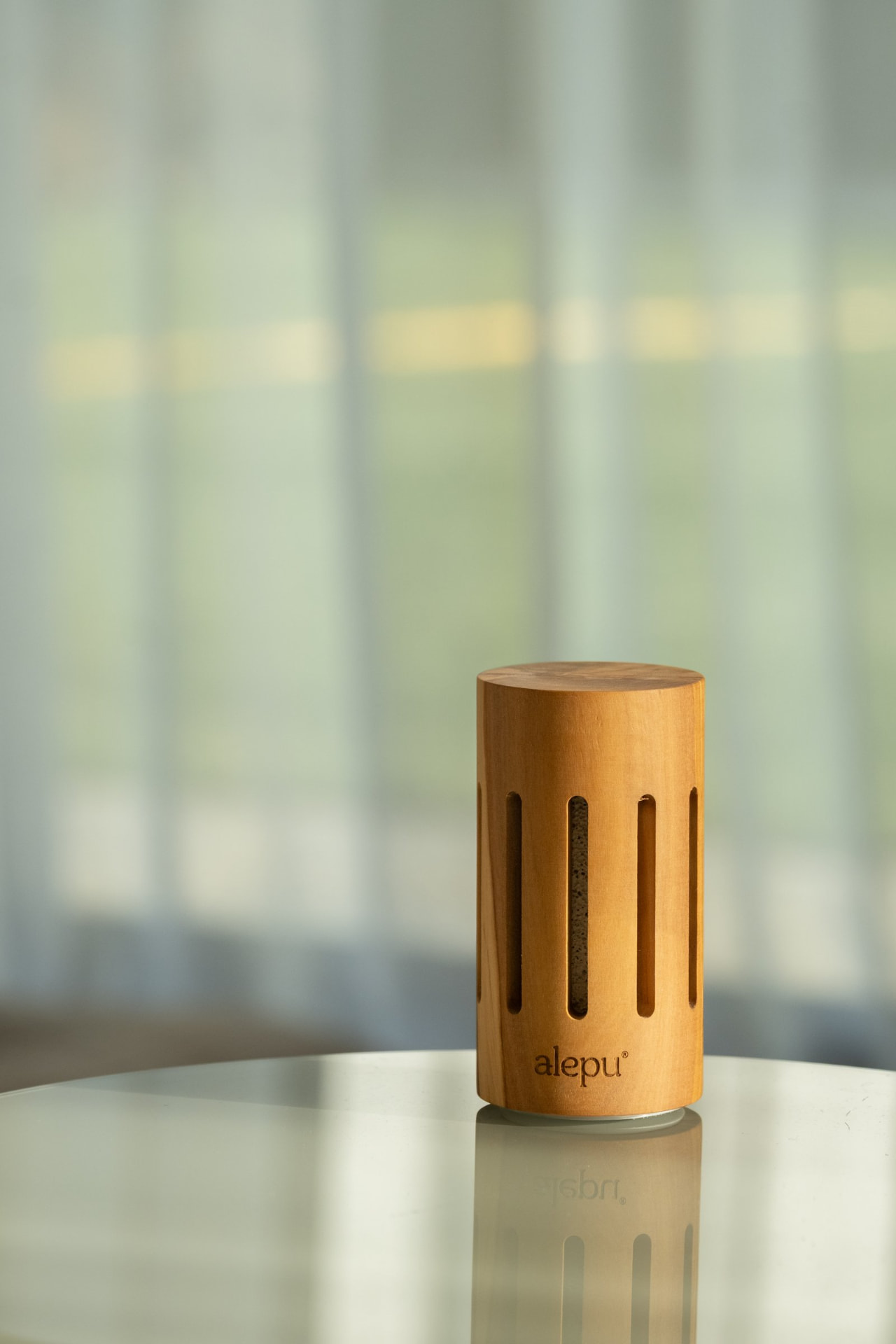 A round olive wood diffuser by a window