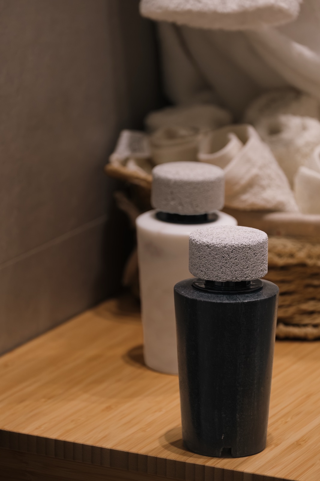 A white and a black marble diffuser beside a basket of rolled towels