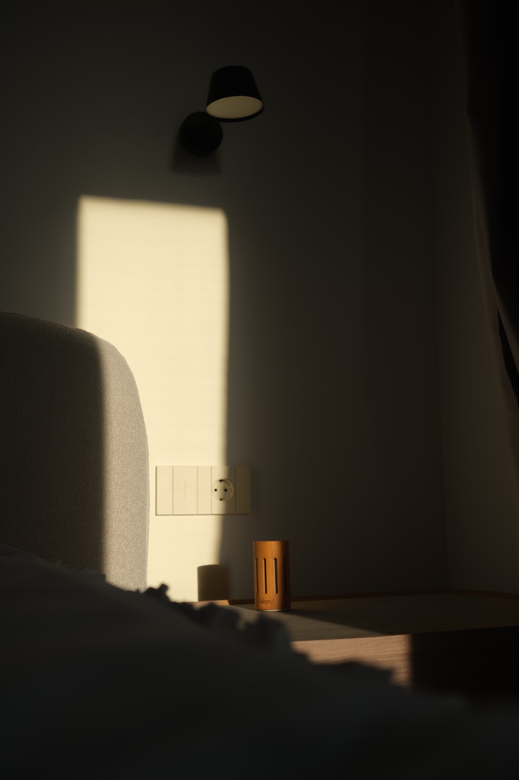 An olive wood diffuser on a bedside table in evening light
